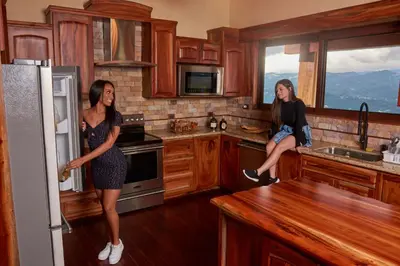 two women standing in a kitchen with a refrigerator at Hotel Pico Colorado in Aserrí