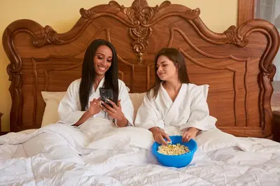two women sitting in bed with a bowl of popcorn at Hotel Pico Colorado in Aserrí