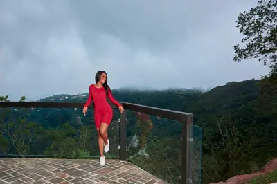 a woman in a red dress standing on a ledge at Hotel Pico Colorado in Aserrí