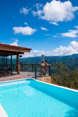 a man and woman sitting next to a swimming pool at Hotel Pico Colorado in Aserrí