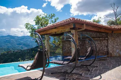 a swimming pool with a gazebo and chairs next to a swimming pool at Hotel Pico Colorado in Aserrí