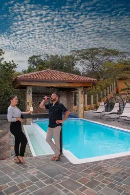 a man and a woman standing next to a swimming pool at Hotel Pico Colorado in Aserrí