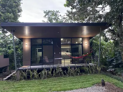 a small house with a hammock in the yard at Bongalow Villa Sarchi in Sarchí