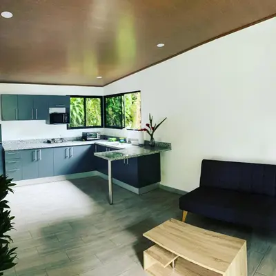 a kitchen with blue cabinets and a black couch at Bongalow Villa Sarchi in Sarchí