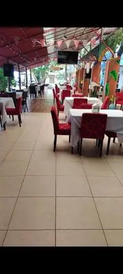 a restaurant with tables and red chairs and tables and tablesearcher at Hotel la Cueva Limon in Puerto Limón