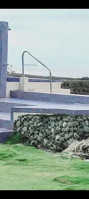 a building with a pile of rocks next to the ocean at Hotel la Cueva Limon in Puerto Limón