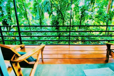 a porch with a chair and a view of a forest at Kinkajoungalows - Amaya Family, Drake Bay, Osa Peninsula in San Pedrillo