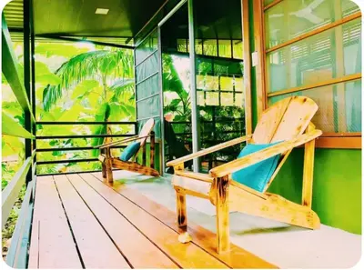 two wooden chairs sitting on the porch of a building at Kinkajoungalows - Amaya Family, Drake Bay, Osa Peninsula in San Pedrillo