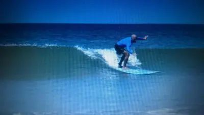 a man riding a wave on a surfboard in the ocean at Gray Beach House in Potrero