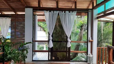 an open door to a patio with curtains at Tropical - Airy, open plan apartment in heart of Santa Teresa in Santa Teresa Beach