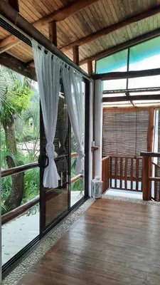 an open glass door with a curtain on a porch at Tropical - Airy, open plan apartment in heart of Santa Teresa in Santa Teresa Beach