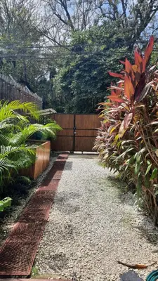 a garden with a fence and a gravel driveway at Tropical - Airy, open plan apartment in heart of Santa Teresa in Santa Teresa Beach