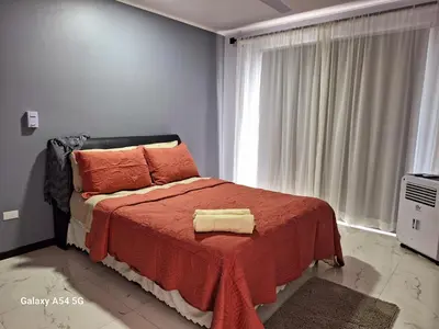 a bedroom with a bed with a red blanket and a window at Victoria House in San Isidro