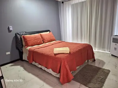 a bedroom with a bed with a red blanket and a window at Victoria House in San Isidro