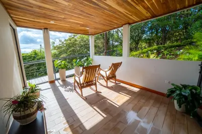 a screened in porch with two chairs and plants at Flower’s Paradise Monteverde in Monteverde Costa Rica