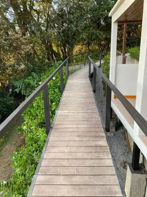 a wooden walkway next to a building with trees at Flower’s Paradise Monteverde in Monteverde Costa Rica