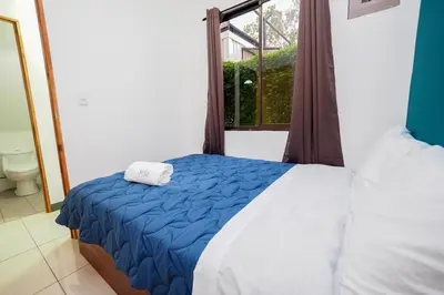 a bedroom with a bed with a blue blanket and a window at Hotel Sirius Costa Rica in San Mateo