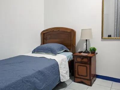 a bedroom with a bed and a table with a lamp at Entire Comfy apartment for you, 5 min SJO Airport in Alajuela City
