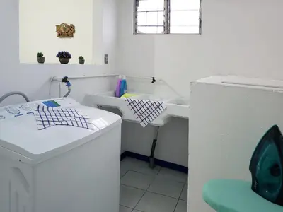 a bathroom with a sink and a washing machine at Entire Comfy apartment for you, 5 min SJO Airport in Alajuela City