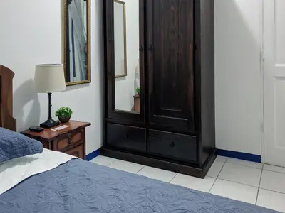 a bedroom with a bed and a wooden cabinet at Entire Comfy apartment for you, 5 min SJO Airport in Alajuela City