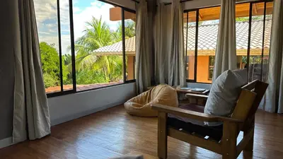 a living room with a chair and large windows at Montezuma Hills - Twin Houses in private compound - 4' to Downtown in Montezuma