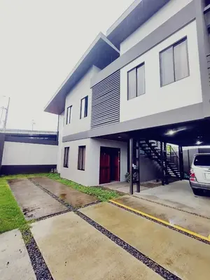 a white building with a car parked in a parking lot at Villas del General in San Isidro