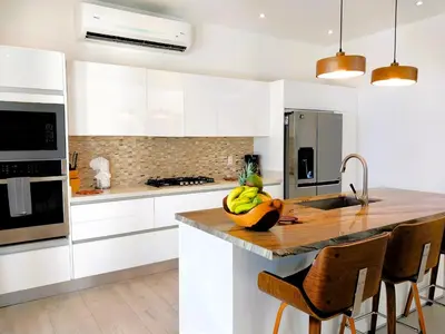 a kitchen with white cabinets and a bowl of bananas on the counter at Casa de Iluminacion - Gorgeous 5-BR oceanview Villa with private infinity Pool in Brasilito
