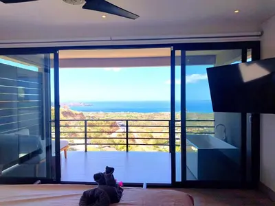a teddy bear sitting on a bed in a room with a large glass door at Casa de Iluminacion - Gorgeous 5-BR oceanview Villa with private infinity Pool in Brasilito