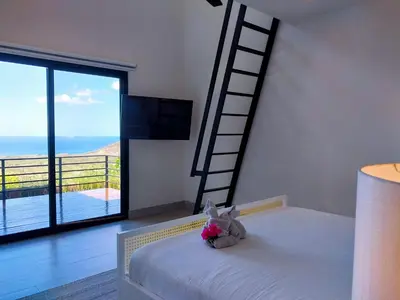 a bedroom with a ladder and a bed with flowers on it at Casa de Iluminacion - Gorgeous 5-BR oceanview Villa with private infinity Pool in Brasilito