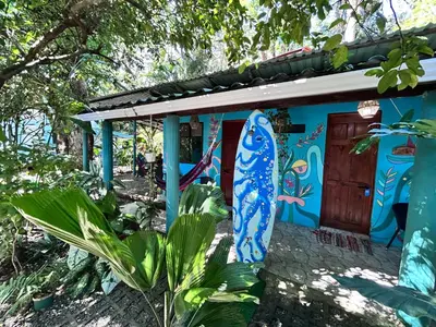 a blue house with a surfboard painted on it at Boutique Rooms River Front at La Junta in Dominical