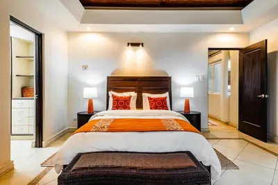 a bedroom with a large bed with red pillows at LUXURY 3BR appt, CENTER, 2 min to BEACH, hi-speed wifi in Tamarindo