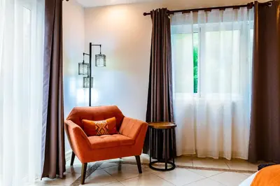an orange chair in a room with a window at LUXURY 3BR appt, CENTER, 2 min to BEACH, hi-speed wifi in Tamarindo