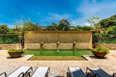 a pool of water in a courtyard with chairs at LUXURY 3BR appt, CENTER, 2 min to BEACH, hi-speed wifi in Tamarindo