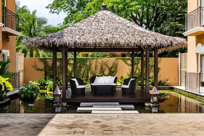 a gazebo with couches and a straw roof at LUXURY 3BR appt, CENTER, 2 min to BEACH, hi-speed wifi in Tamarindo