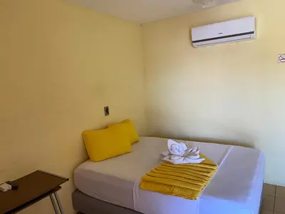 a room with a bed with a towel and a flower on it at Hotel Real Alaska in Liberia