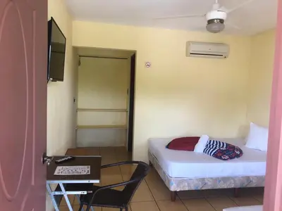 a bedroom with a bed and a table and a television at Hotel Real Alaska in Liberia