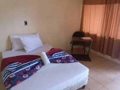 a bedroom with two beds and a table and a window at Hotel Real Alaska in Liberia