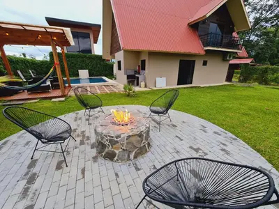 a patio with three chairs and a fire pit at Volcano view house la Fortuna in Fortuna