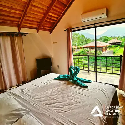 a bed with a ribbon on it in a room with a window at Volcano view house la Fortuna in Fortuna