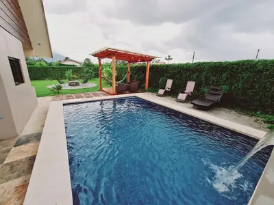 a swimming pool with two chairs and a gazebo at Volcano view house la Fortuna in Fortuna