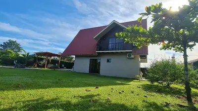 a house with a red roof and a green yard at Volcano view house la Fortuna in Fortuna