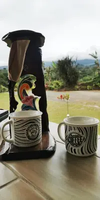 two coffee cups sitting on a table with a bag at Dreamcatcher House Bus Experience 2 in Sarchí