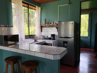 a kitchen with a refrigerator and a counter with stools at Casita el jardin in Bijagua