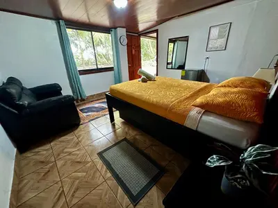 a bedroom with a bed and a couch and a chair at Caribbean View in Tortuguero