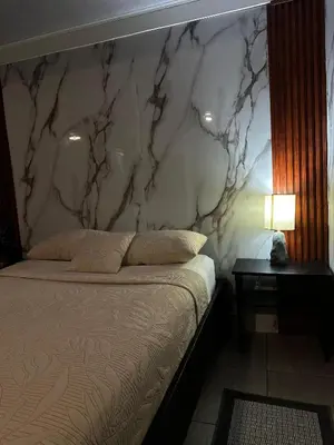 a bedroom with a marble wall with a bed and a table at Caribbean View in Tortuguero