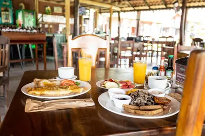 a table with two plates of food and orange juice at Hotel El Rancho in Quepos