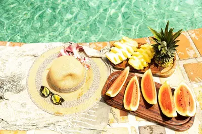 a table with a straw hat and a plate of fruit at Hotel El Rancho in Quepos