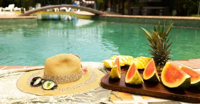 a hat and a plate of fruit next to a pool at Hotel El Rancho in Quepos