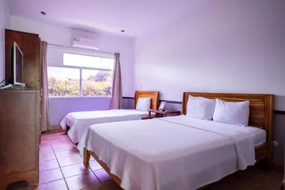 a hotel room with two beds and a window at Hotel El Rancho in Quepos