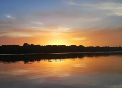 a sunset over a body of water with trees at Hotel Casa THIREMA Tortuguero in Tortuguero
